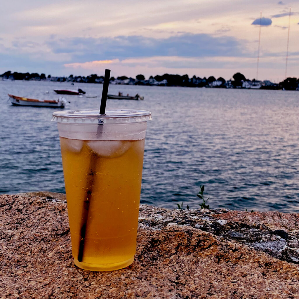 A clear cup filled with iced tea and a black compostable, marine-degradable straw.