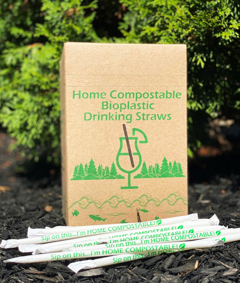 A brown paper box with green print stands behind a pile of paper-wrapped, custom manufactured, white-label compostable straws.