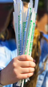A hand holds several wrapped compostable straws.